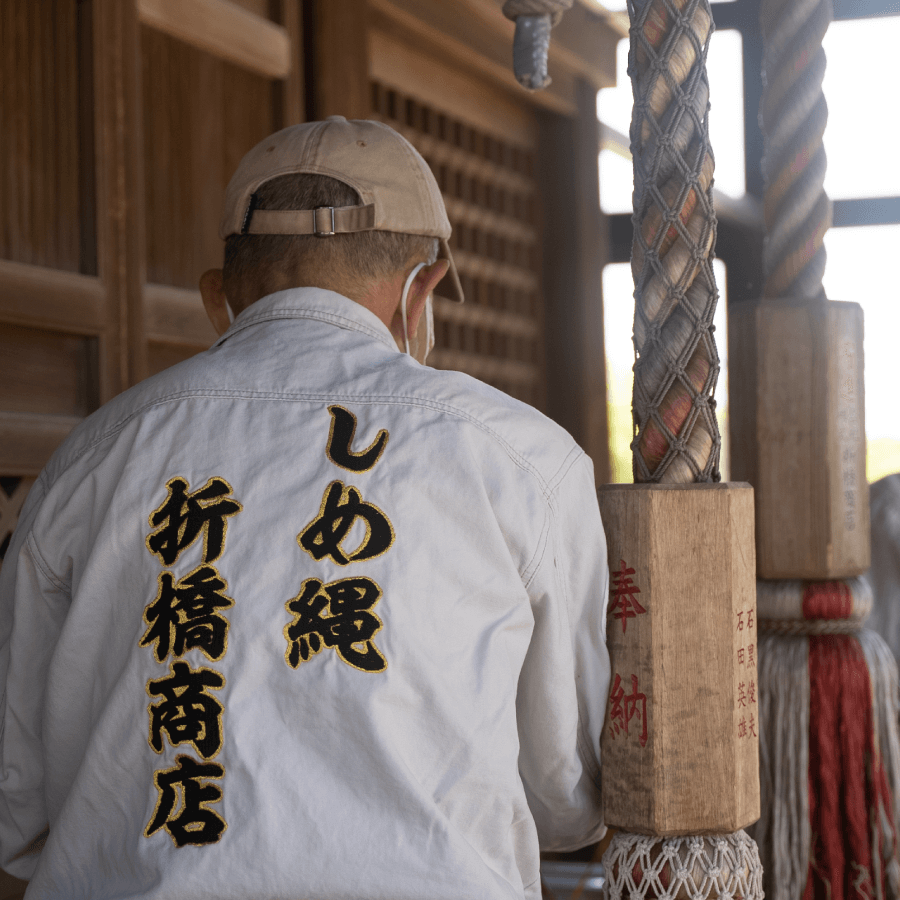 株式会社折橋商店_神社の鳥居に合繊しめ縄を取り付けている様子